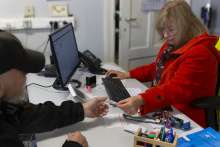 Photo : Au bureau social, l’assistante sociale tend un ticket à un bénéficiaire. Ce ticket lui permettra d’accéder au service repas. Par respect pour la vie privée, le visage du bénéficiaire est flouté.