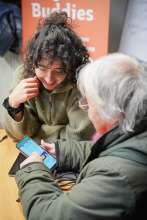 Une jeune personne accompagne une personne plus âgé dans la maîtrise de son téléphone