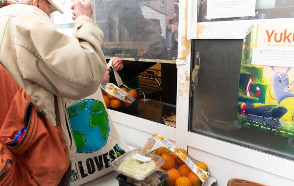 Photo : Un bénéficiaire ouvre son sac eco pour recevoir le plat sous vide et les denrées du jour, distribués par des bénévoles. Par respect pour la vie privée, le visage du bénéficiaire n'est pas visible.