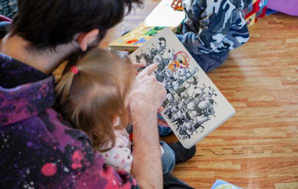 Photo d'un adulte présentant un livre à une jeune enfant.