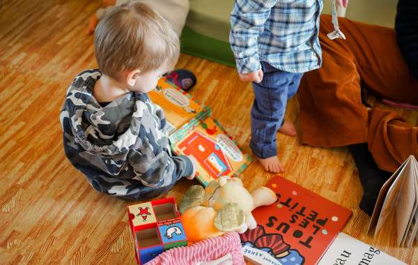 Un jeune enfant de 2 ans regarde un livre. Il est assis par terre