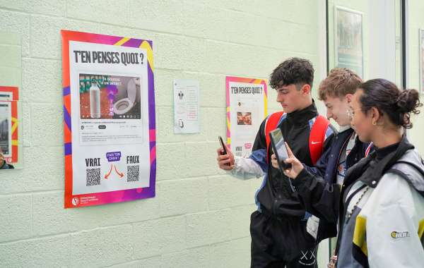 Des jeunes regardent un poster qui les interroge si une informations est vraie ou fausse. Ils utilisent leur téléphone pour choisir leur réponse